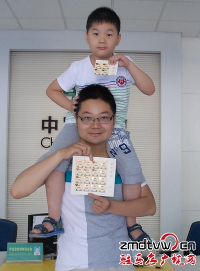 圖為6月13日，一對父子在市中心郵政所展示“感恩父親”特種郵票 .JPG