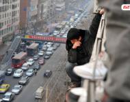 圖為2014年1月3日，蘭州，6名農(nóng)民工為了討薪爬上白銀路一居民樓9樓平臺要“跳樓”。原來，該樓4層的甘肅天安建筑機械工程公司拖欠24名工人的24萬元工錢，他們討要5個月毫無結(jié)果，便做出危險之舉。后經(jīng)有關部門多方協(xié)調(diào)，工人們當場拿到了18萬元。于永昭/視覺中國