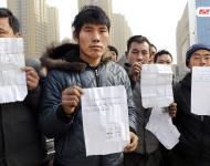 承建商已將工程款給付90%，但包工頭宋林卻把錢拿走不給工人結(jié)工資。一氣之下，十多名工人將包工頭車和人扣下，一不留神卻讓包工頭翻墻跑了。2015年12月31日，在勞動監(jiān)察部門協(xié)調(diào)下達成初步協(xié)議，包工頭將工人手續(xù)移交到成泰公司，由成泰公司替宋林代付一半工資，但在移交工人手續(xù)的時候包工頭害怕再次被扣卻一直不敢露面。1月3日，包工頭給農(nóng)民工發(fā)來短信，并要求寫下承諾書，保證不扣他本人。圖為1月5日，陜西商洛，討薪農(nóng)民工在工地上出示欠條和他們寫給包工頭的承諾書。華商報記者 閆文青/視覺中國