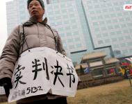 2006年1月24日，在京從事降水井工程的老陳掛著寫有“賣判決書”的紙口袋在北京站口附近來回走著。曾是名小工頭的老陳被欠工程款4萬元，為了給工人們開資不得已賣掉了打井機器。2002年法院宣判老陳勝訴，可四年后該判決仍得不到執(zhí)行，無奈之中老陳只好上演此幕。程寧/視覺中國